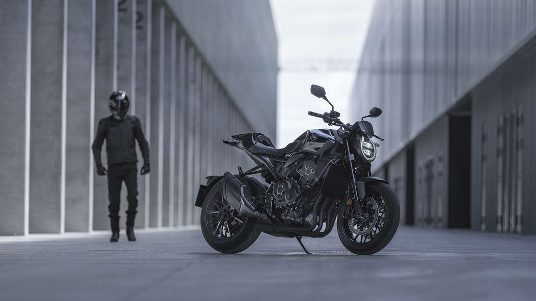 Honda CB1000R Black Edition - man standing next to the bike in the street between buildings