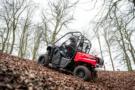 Honda Pioneer 520 going up a hill covered in leaves