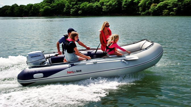 side view of people steering honwave inflatable boat fitted with honda marine engine