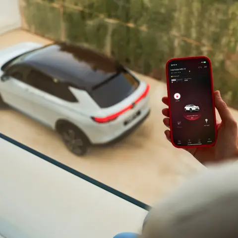 Close up of person with a phone using the My Honda + App with Honda HR-V outside window