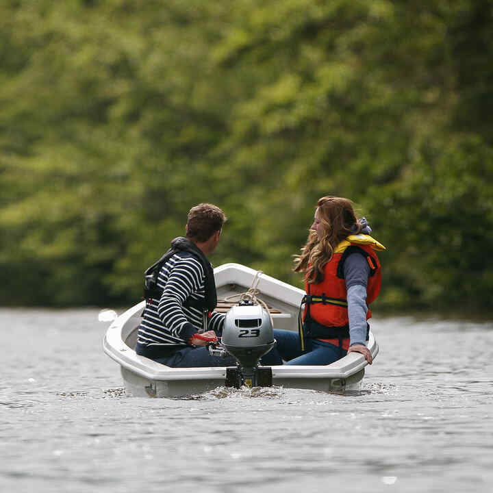 Two people in a boat on the water using a BF2.3 engine.