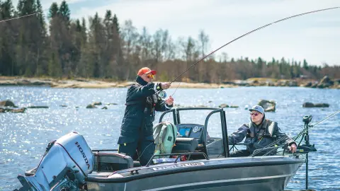 Gentlmen fishing from a boat with Honda BF30 engine in lake location.