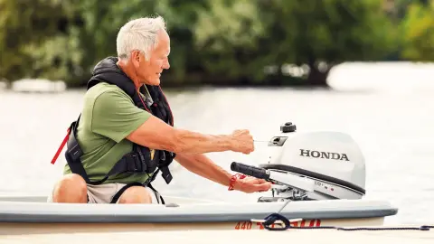 Gentleman on a boat starting a Honda BF5 engine.