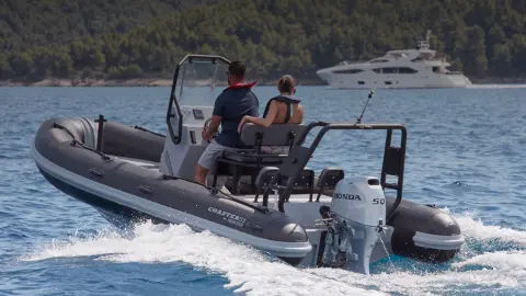 Couple on a rear facing Highfield boat with BF50 engine in ocean location.