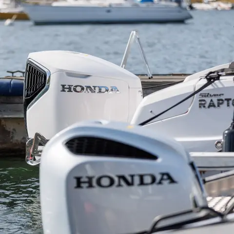 Close up of Honda engines on the backs of boats in water location. 