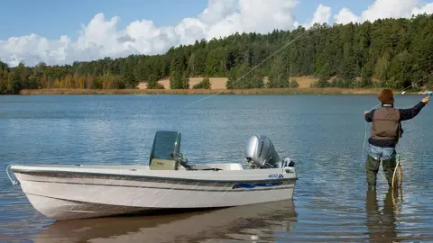 Model fishing in the lake with boat nearby showcasing the BF8-10 engine.