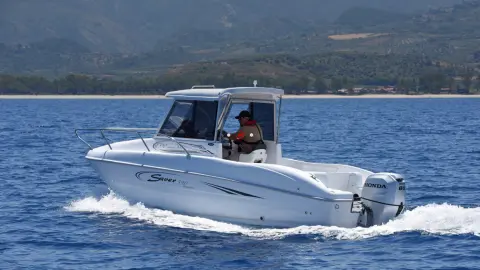 Model driving a boat with the BF80-100 engine in a sea location.