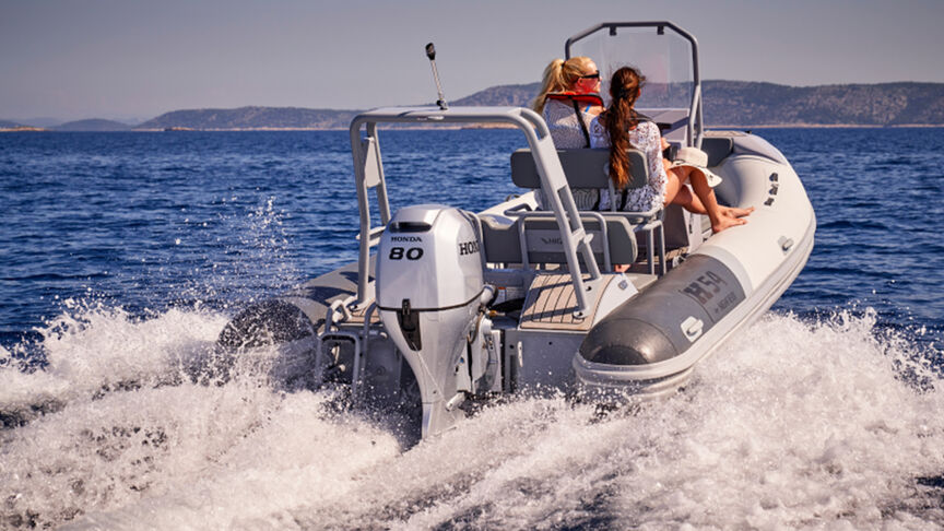 Model steering a boat in a sea location with the BF80-100 engine.