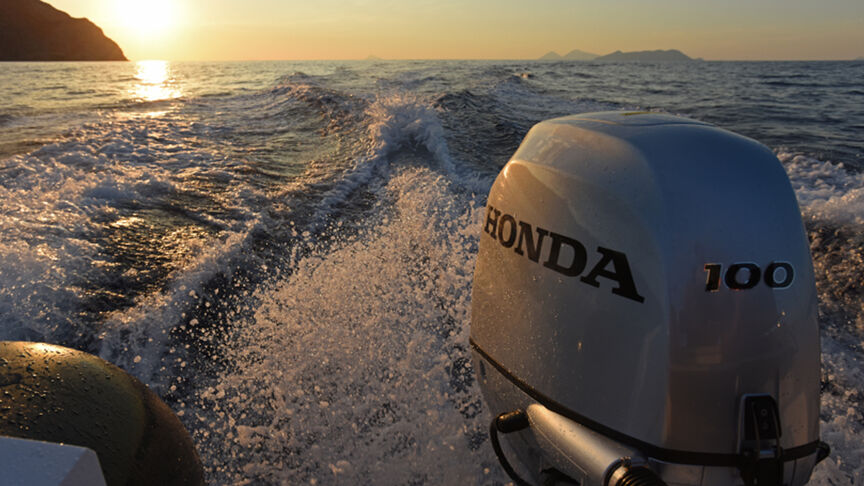 Model steering a boat in a sea location with the BF80-100 engine.