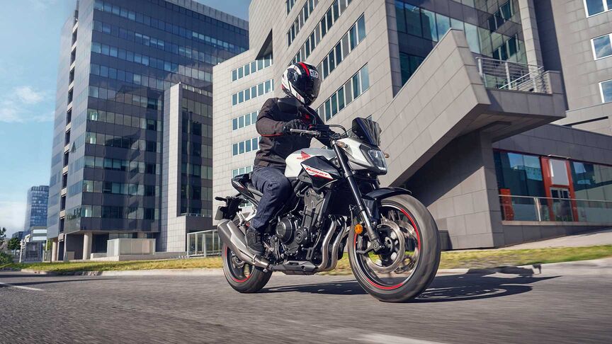 Model riding a motorcycle in a city location.